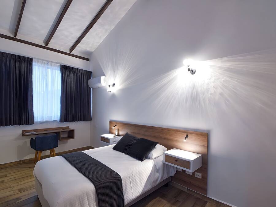 Una habitación de hotel moderna con una cama grande, mesitas de noche, un escritorio y una silla.