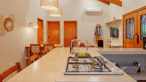 A kitchen with a long countertop, wooden chairs, a gas stove, and hanging pendant lights. - YELLOW HOUSE - (House for up to 8 people.) (Solar dos Lagos II Bonito)