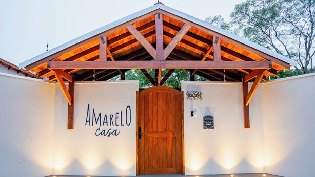 A building entrance with a wooden door, a sign reading "Amarelo Casa," and a number "294" on the wall. - YELLOW HOUSE - (House for up to 8 people.) (Solar dos Lagos II Bonito)