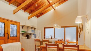 A spacious living area with a high wooden ceiling, a dining table with chairs, a sofa, and a kitchen in the background. - YELLOW HOUSE - (House for up to 8 people.) (Solar dos Lagos II Bonito)