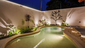 A swimming pool with a curved edge, surrounded by plants and a decorative tree sculpture. - YELLOW HOUSE - (House for up to 8 people.) (Solar dos Lagos II Bonito)
