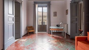 Ein Zimmer mit großem Fenster, einem Sessel, einem Schreibtisch und einer Couch.