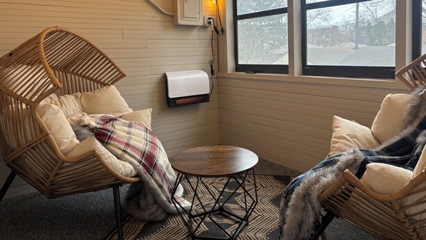 A cozy room with wicker chairs, a small round table, and a heater on the wall.