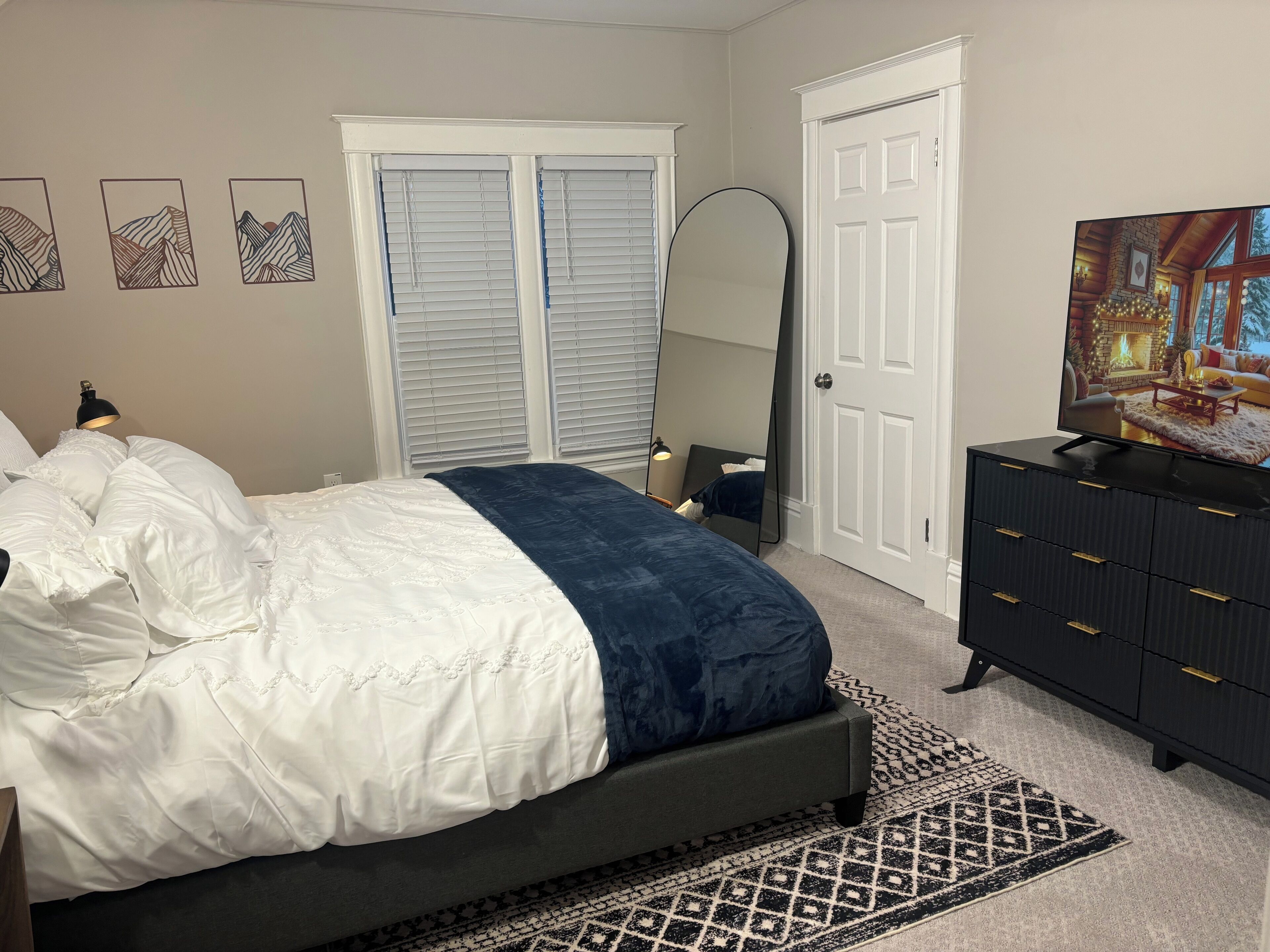 A bedroom with a bed, a dresser, a mirror, and a television.