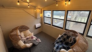 A cozy room with two wicker chairs, a small table, and a window with a view of the outside.