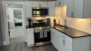 A compact kitchen with white cabinets, a stainless steel stove, a microwave, and a sink.