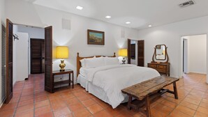 A bedroom with a bed, bedside tables, a wooden bench, a painting on the wall, and a mirror. - Charlie IV House at Y.O. Ranch Headquarters - 4-Bedroom Ranch Stay (Mountain Home)