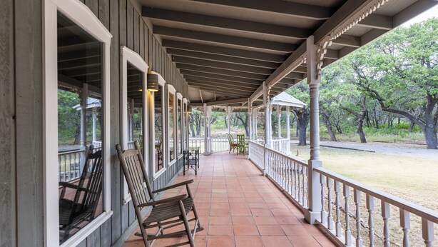 A covered porch with wooden rocking chairs and a tiled floor. - Charlie IV House at Y.O. Ranch Headquarters - 4-Bedroom Ranch Stay (Mountain Home)