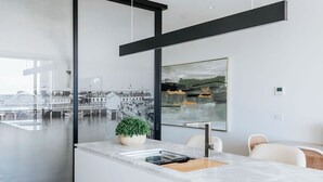 A modern kitchen with a large island, a built-in oven, and a view of a cityscape through a glass wall. - Sunlit Sorrento Splendour in Position Perfect (Sorrento)