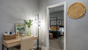 A modern bedroom with a bed, bedside table, and a mirror.