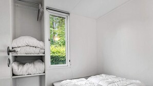 Ein schlicht eingerichtetes Schlafzimmer mit Bett, Kleiderschrank und Fenster.