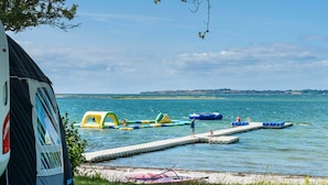 A lakeside campsite with a tent, floating play structures, and a dock extending into the water. - 8 Person Holiday Park Home in Faaborg (Faaborg)