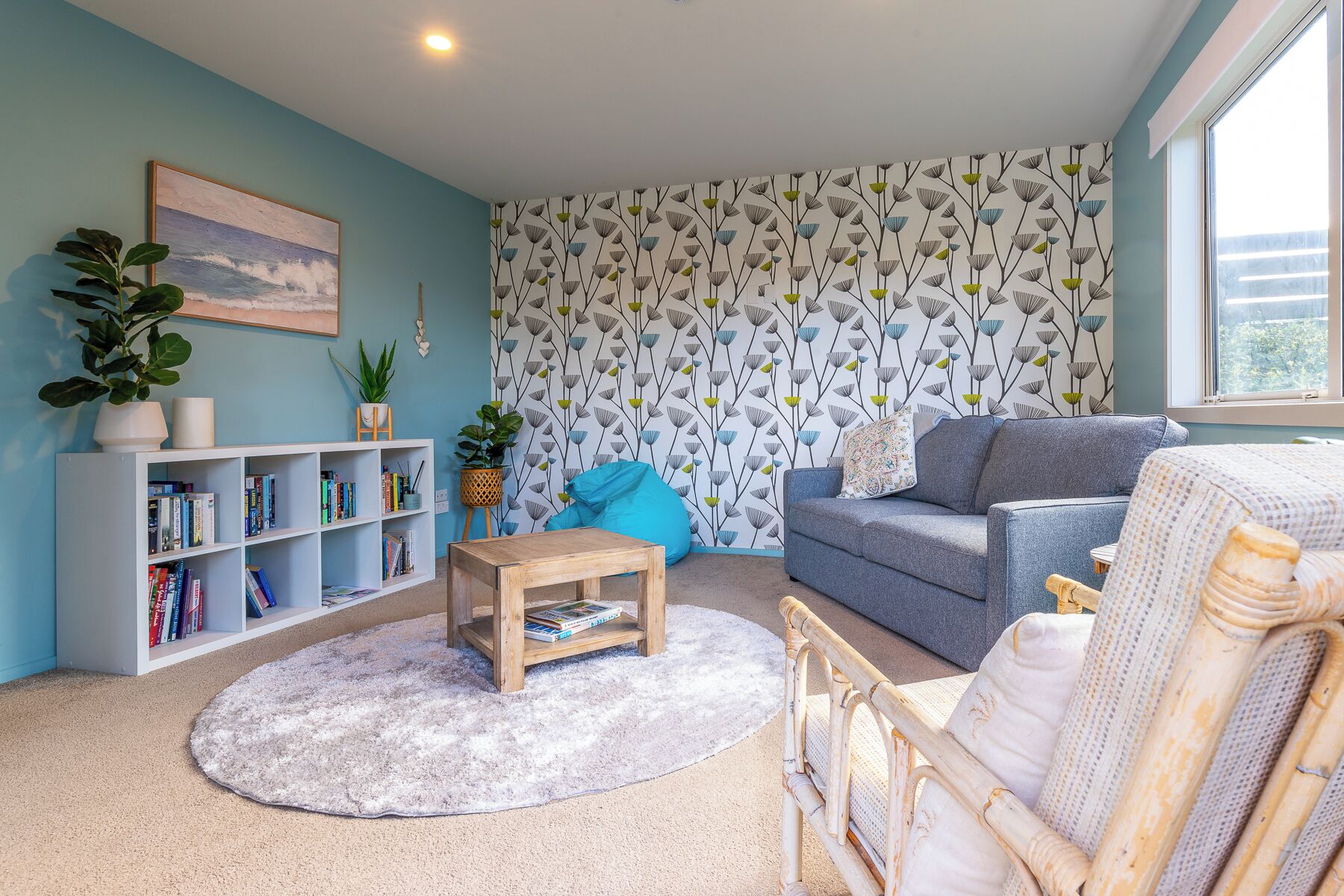 Een gezellige woonkamer met een boekenkast, een salontafel, een bank en een fauteuil.