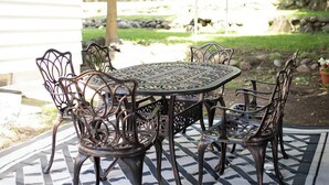 A patio with a round metal table and chairs, surrounded by a patterned rug. - The West Quincy House: In Town with Sauna + Garage (Hancock)