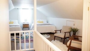 A small, cozy bedroom with two beds, a chair, and a small table. - The West Quincy House: In Town with Sauna + Garage (Hancock)