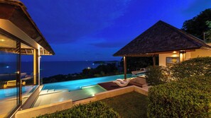 Uma área moderna com piscina ao ar livre, com lounge envidraçado e área de estar coberta, com vista para o oceano.