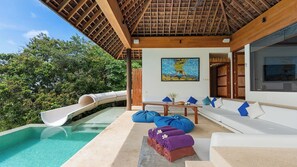 Uma área à beira da piscina com escorrega, sofás e mesa com toalhas.