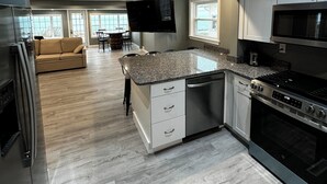 Una cocina moderna con encimeras de granito, electrodomésticos de acero inoxidable y un comedor con sofá y sillas.