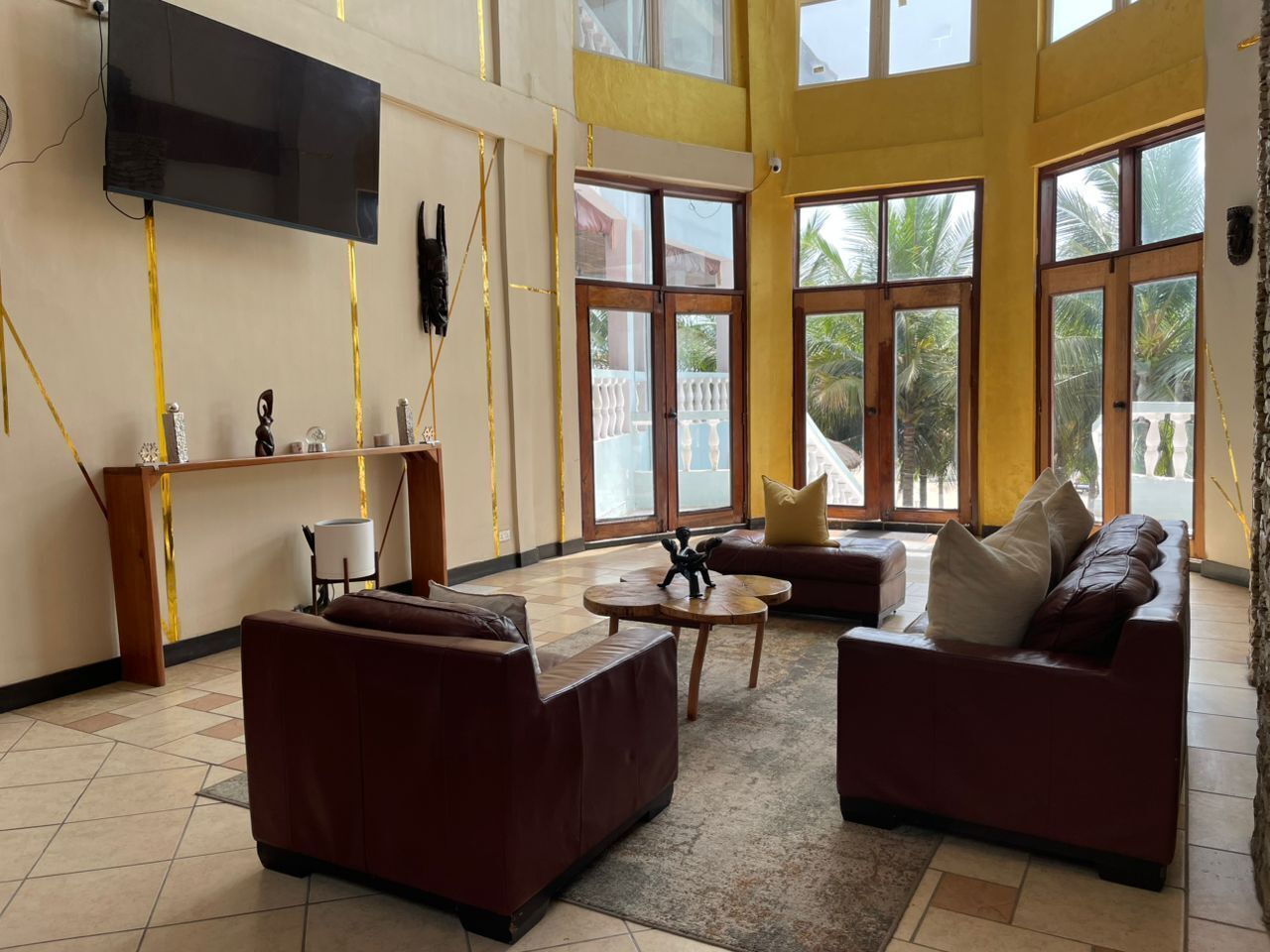 A spacious living area with a flat-screen TV mounted on the wall, a wooden reception desk, and a seating arrangement including a sofa and a loveseat.