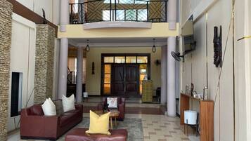 A spacious lobby with a high ceiling, a stone accent wall, a red leather sofa, and a wooden console table.