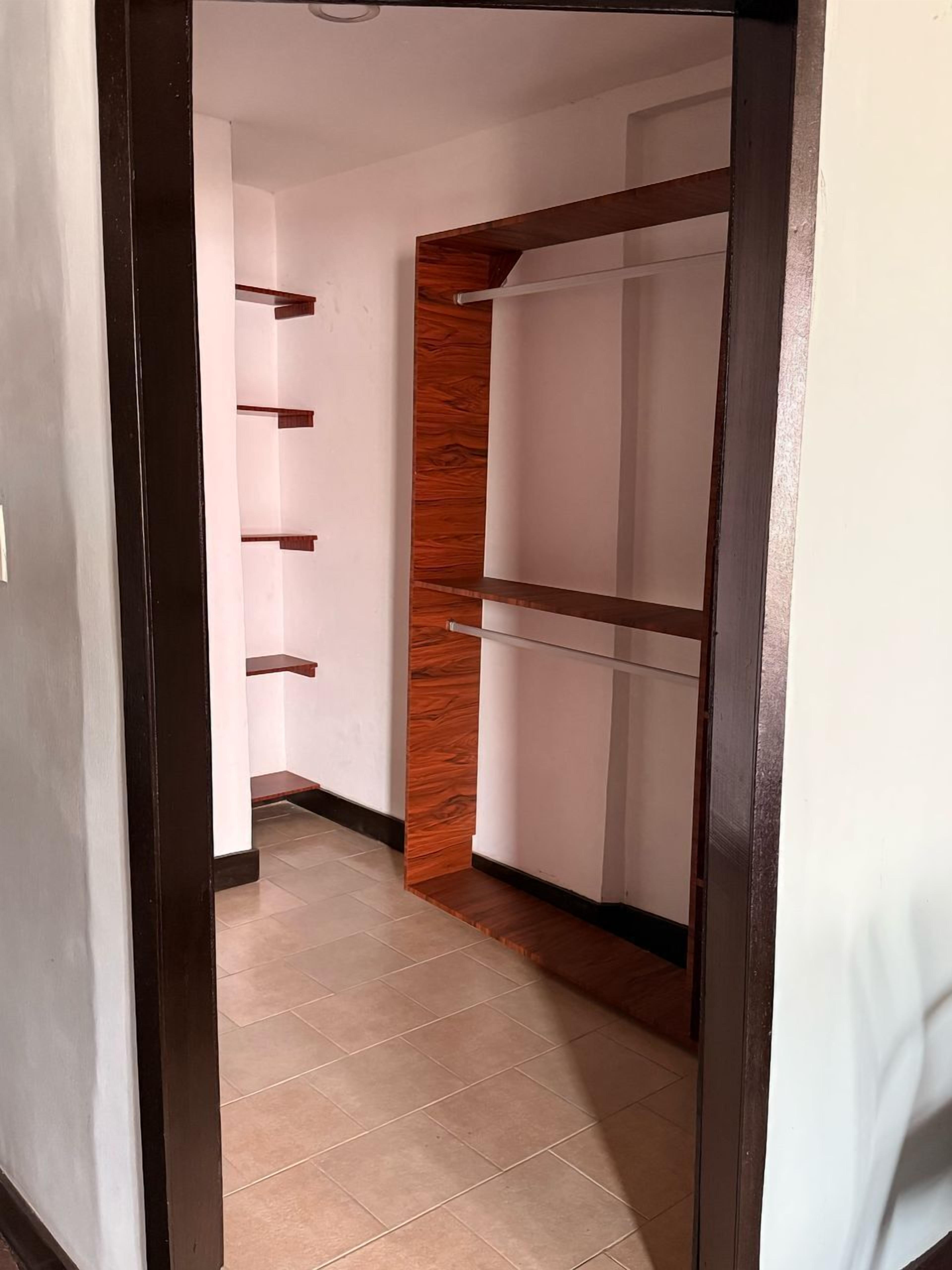 A hallway with a wooden accent wall, white walls, and a tiled floor.