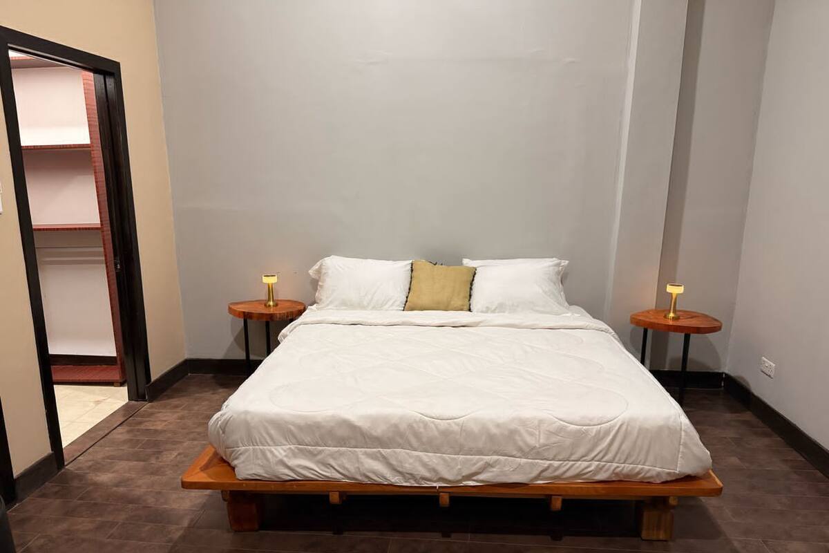 Ein Schlafzimmer mit einem Bett aus Holz, weißer Bettwäsche und zwei Nachttischen mit Lampen.