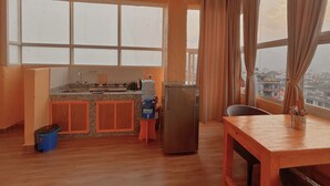 A kitchen with a window, a table, and a refrigerator. - Nishan Apartments and Home (Pokhara)