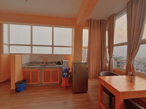 A kitchen with a window, a table, and a refrigerator. - Nishan Apartments and Home (Pokhara)
