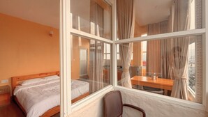 A hotel room with a bed, a chair, and a table by a window with curtains. - Nishan Apartments and Home (Pokhara)