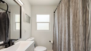 Un baño con tocador blanco, inodoro y cortina de ducha.
