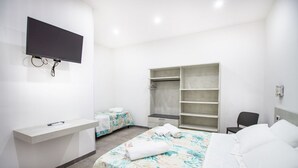 A hotel room with a bed, a desk, a TV, a wardrobe, and a small seating area. - S'Omu e Chicchinu rooms (Cardedu)