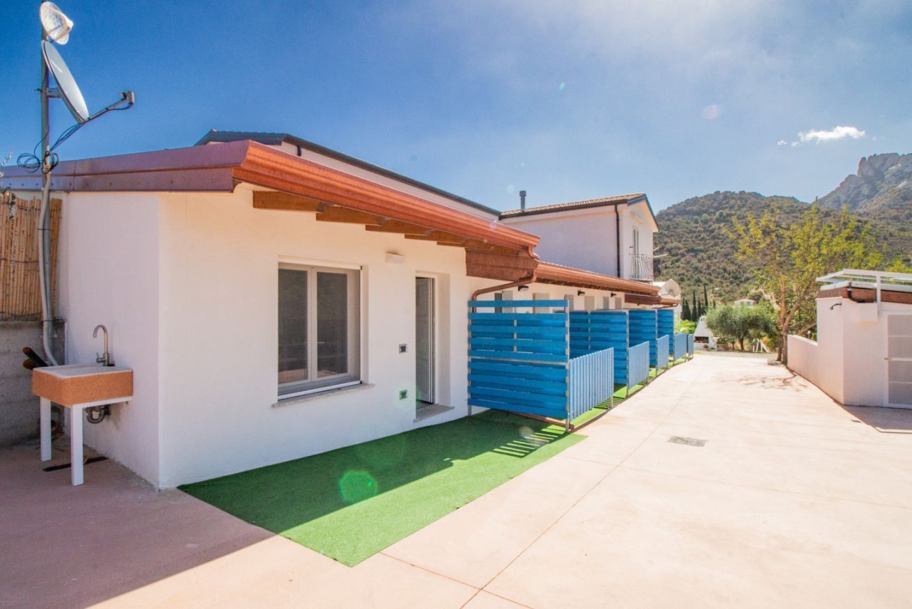 Uma casa moderna com um pequeno pátio, antena parabólica e vista para a montanha.