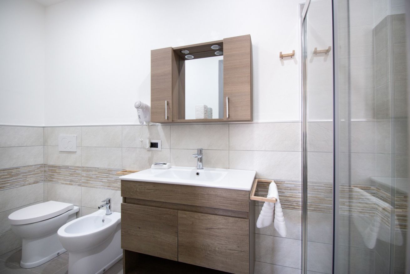 Ein modernes Badezimmer mit einem weißen Waschbecken, einem Holz-Badmöbel und einer Glasdusche.