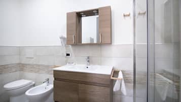 Ein modernes Badezimmer mit einem weißen Waschbecken, einem Holz-Badmöbel und einer Glasdusche.
