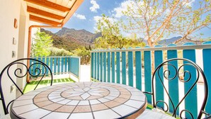 Un patio con mesa y sillas de baldosas, techo de madera y vistas a montañas y árboles.