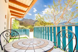 Une terrasse avec une table et des chaises carrelées, un plafond en bois et une vue sur les montagnes et les arbres.
