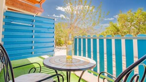 Un patio con una cerca azul, una mesa redonda con una botella y una silla.