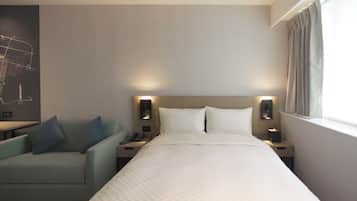 A hotel room with a bed, a nightstand, a lamp, a chair, and a wall-mounted map.