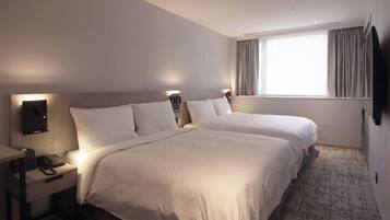 Ein Hotelzimmer mit zwei Betten, einem Schreibtisch mit Telefon und einem an der Wand befestigten Fernseher.
