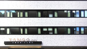 Een gebouw met een moderne gevel, meerdere ramen met gordijnen en een bord waarop 