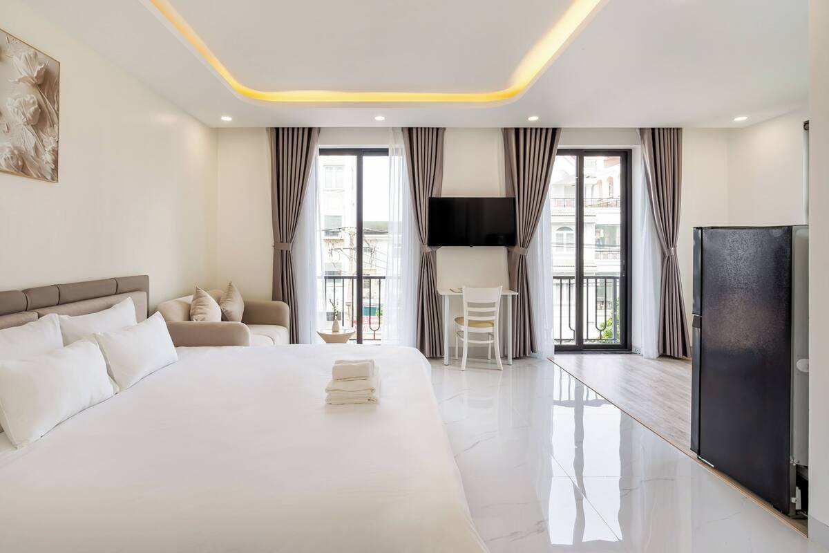 Une chambre d’hôtel moderne dotée d’un grand lit, d’un coin salon, d’une télévision et d’un balcon avec des rideaux.