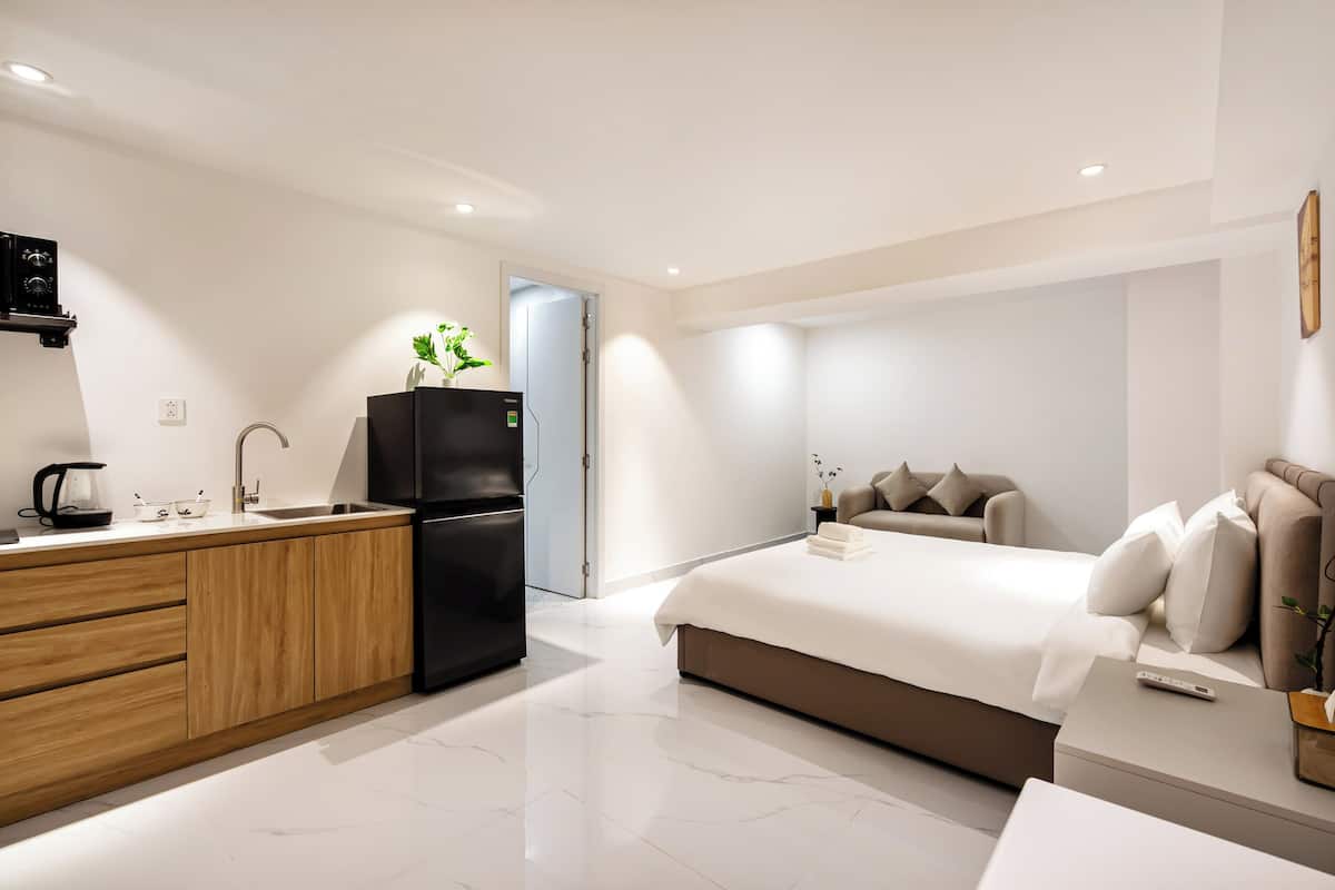 Une chambre d’hôtel moderne équipée d’une kitchenette, d’un lit et d’une table de chevet.