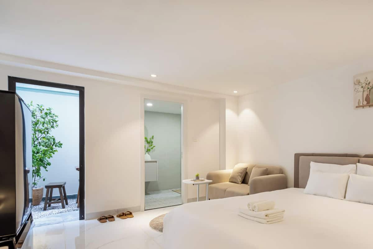 Une chambre d’hôtel moderne avec un grand lit, un canapé, une petite table et un téléviseur.