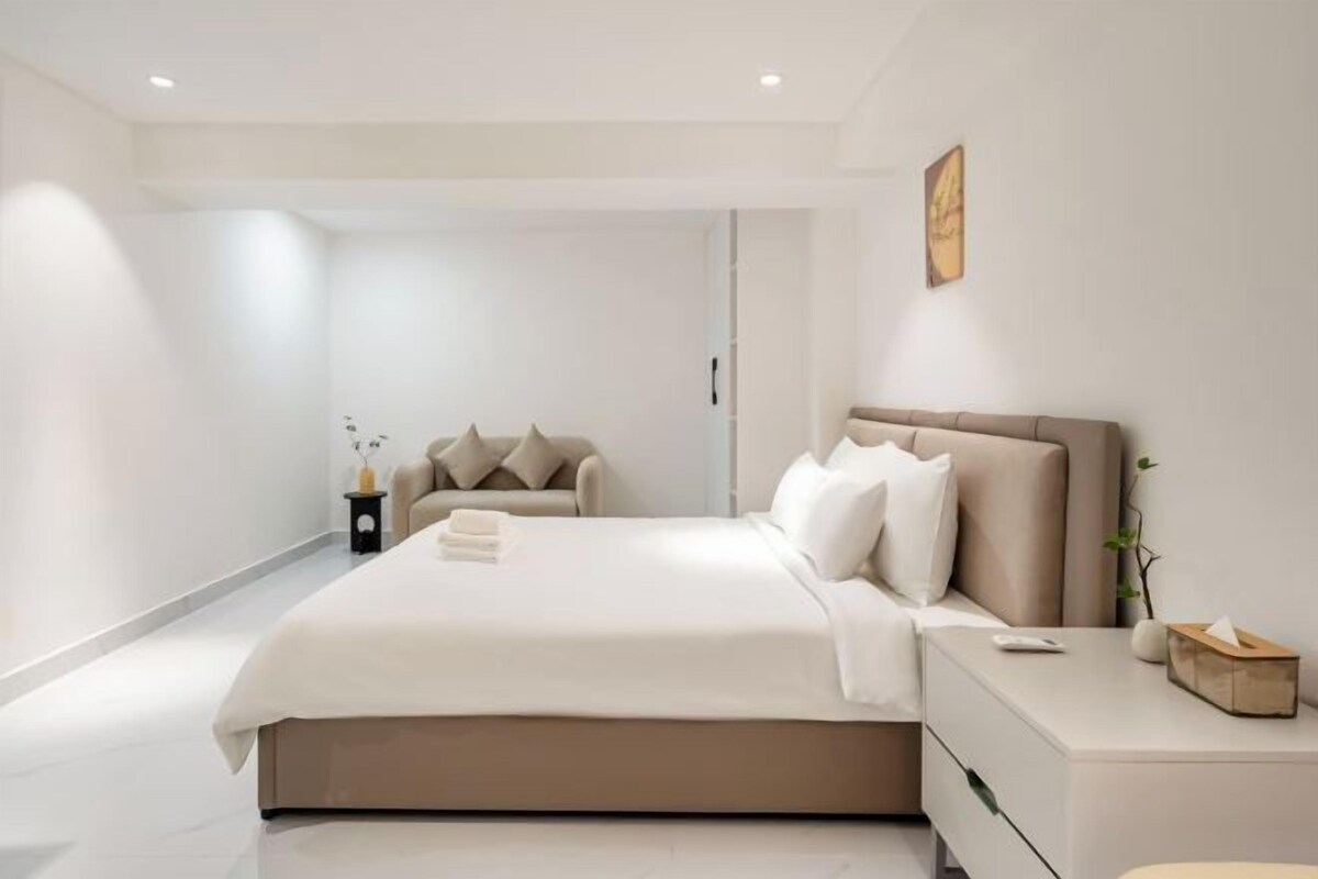 Un dormitorio moderno con una cama grande, una mesita de noche y un buró.