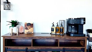 A wooden coffee station with a wall sign saying "but first coffee" and a coffee machine. - The Luxe Loft in Canal Park | Boho-Chic (Duluth)