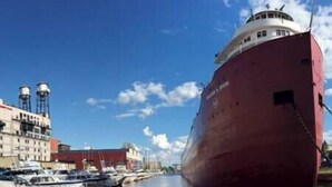 A large red ship docked at a marina with several smaller boats and buildings in the background. - The Luxe Loft in Canal Park | Boho-Chic (Duluth)