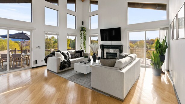 A spacious living area with a fireplace, large windows, and a balcony with outdoor furniture.