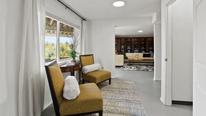 A modern living room with a sofa, two armchairs, a coffee table, and a view of a dining area.