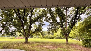 A covered patio area with a view of a grassy park and trees. -  NO CLEANING FEE Century farmhouse on Lake Keowee near Clemson (Seneca)