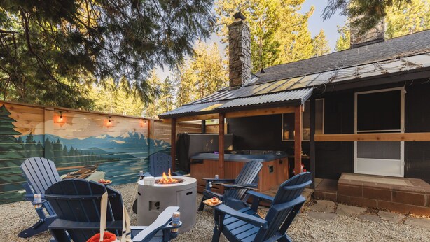 An outdoor seating area with Adirondack chairs, a fire pit, and a hot tub.